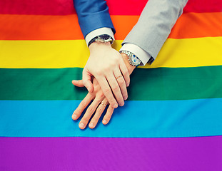 Image showing close up of male gay couple hands on rainbow flag