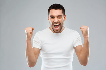 Image showing young man celebrating victory over gray