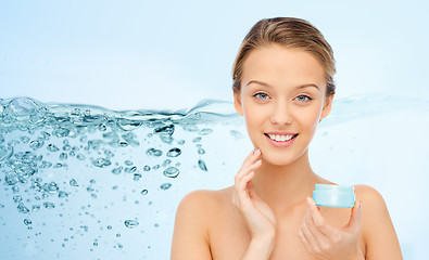 Image showing happy young woman applying cream to her face