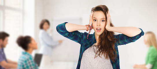 Image showing teenage student girl holding to head at school