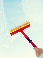 Image showing close up of hand cleaning window with sponge