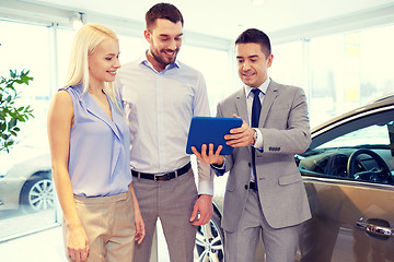 Image showing happy couple with car dealer in auto show or salon