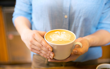 Image showing close up of hands with latte art in coffee cup