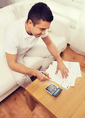 Image showing man with papers and calculator at home