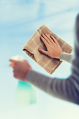 Image showing close up of woman hands cleaning window with cloth