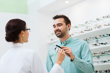 Image showing optician showing glasses to man at optics store