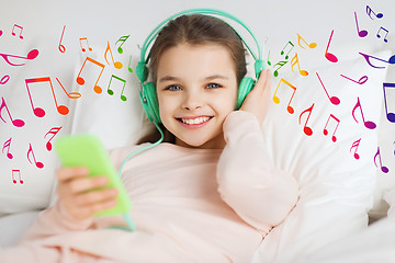 Image showing happy girl in bed with smartphone and headphones