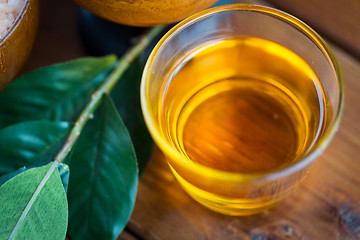 Image showing close up of honey in glass with leaves on wood