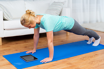 Image showing woman with tablet pc doing plank exercise at home