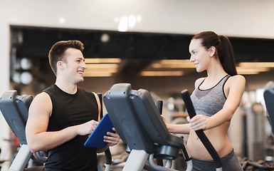 Image showing woman with trainer exercising on stepper in gym