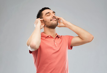 Image showing happy man listening to music over gray background