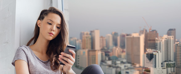 Image showing sad pretty teenage girl with smartphone texting