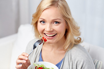Image showing smiling middle aged woman eating salad at home