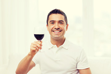 Image showing happy man drinking red wine from glass at home