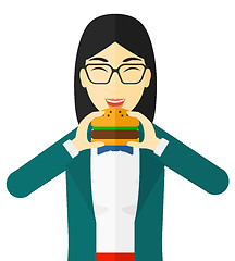 Image showing Woman eating hamburger. 