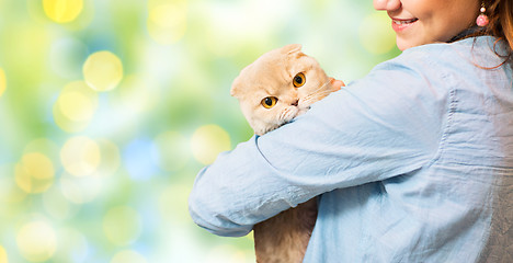 Image showing happy woman holding scottish fold cat over green