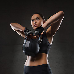 Image showing young woman flexing muscles with kettlebell in gym