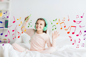 Image showing girl sitting on bed with smartphone and headphones