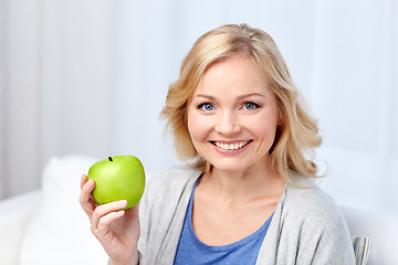 Image showing happy middle aged woman with green apple at home