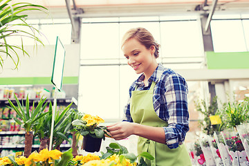 Image showing happy woman holding flowers in greenhouse