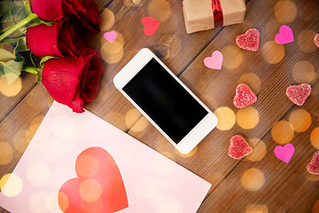 Image showing close up of smartphone, gift, red roses and hearts