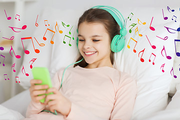 Image showing happy girl in bed with smartphone and headphones