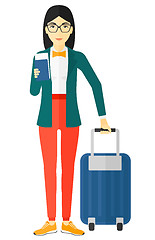 Image showing Woman standing with suitcase and holding ticket.