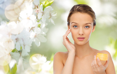 Image showing young woman applying cream to her face