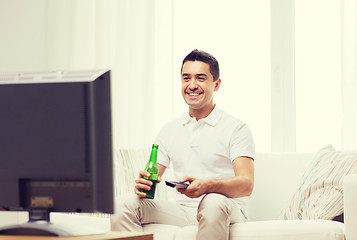 Image showing smiling man watching tv and drinking beer at home