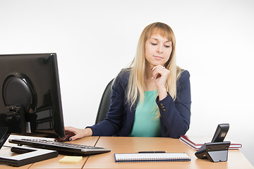 Image showing Secretary working at a computer looking at the phone rang