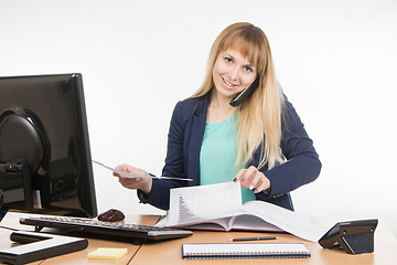 Image showing  Business woman talking on the phone and looking for the desired paper documents