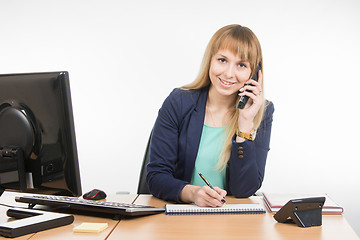 Image showing Business woman talking on the phone, writing in a notebook, and looked into the frame