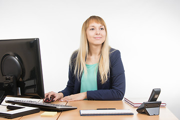 Image showing Beautiful girl secretary working at a computer looked at visitor