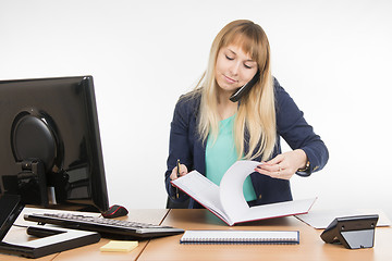Image showing Business woman answering the phone delves into folders with documents