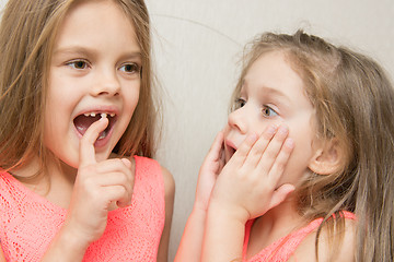 Image showing Six year old girl shows her sister a four wobbly front tooth milk