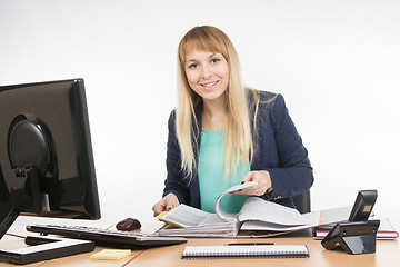 Image showing Secretary leafing through papers in a big folder and looked into the frame