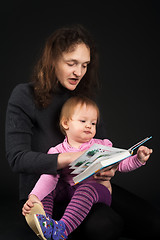 Image showing mother with daughter reading book over black