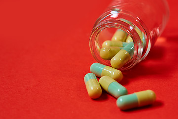 Image showing Pills spilling out of pill bottle on red. Top view with copy space. 