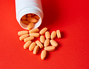 Image showing Pills spilling out of pill bottle on red. Top view with copy space. 