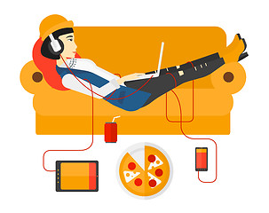 Image showing Woman with gadgets lying on sofa.