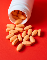 Image showing Pills spilling out of pill bottle on red. Top view with copy space. 