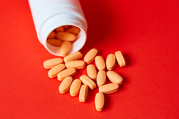 Image showing Pills spilling out of pill bottle on red. Top view with copy space. 