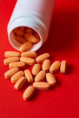 Image showing Pills spilling out of pill bottle on red. Top view with copy space. 