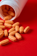 Image showing Pills spilling out of pill bottle on red. Top view with copy space. 