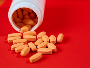 Image showing Pills spilling out of pill bottle on red. Top view with copy space. 