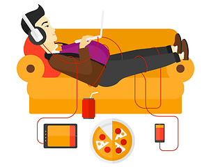 Image showing Man with gadgets lying on sofa.