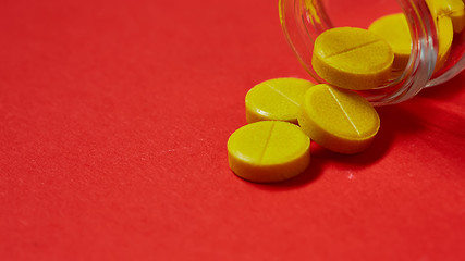 Image showing Pills spilling out of pill bottle on red. Top view with copy space. 