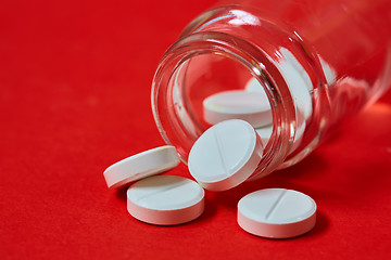 Image showing Pills spilling out of pill bottle on red. Top view with copy space. 