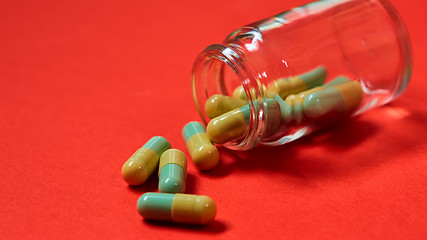 Image showing Pills spilling out of pill bottle on red. Top view with copy space. 