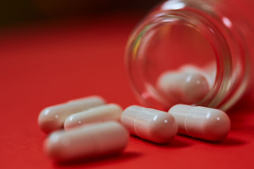 Image showing Pills spilling out of pill bottle on red. Top view with copy space. 